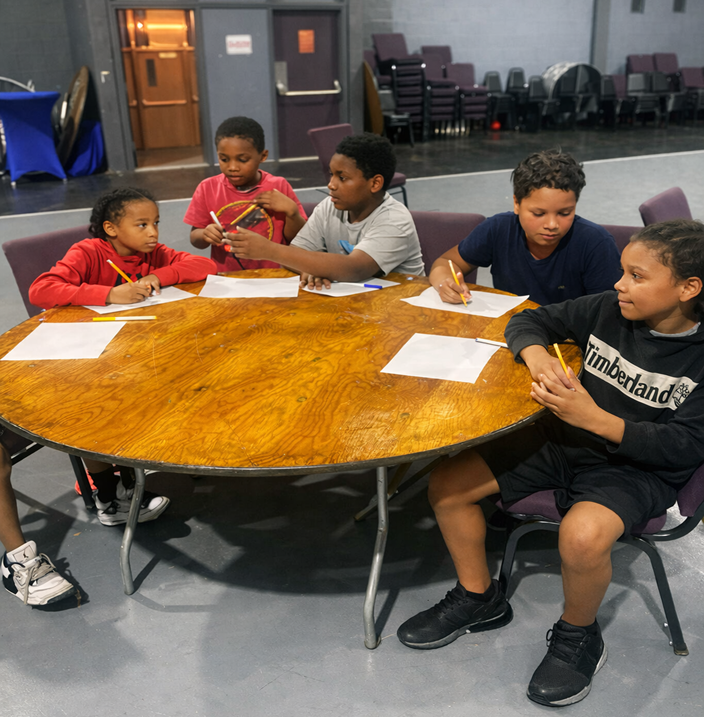 Youth at table writing together